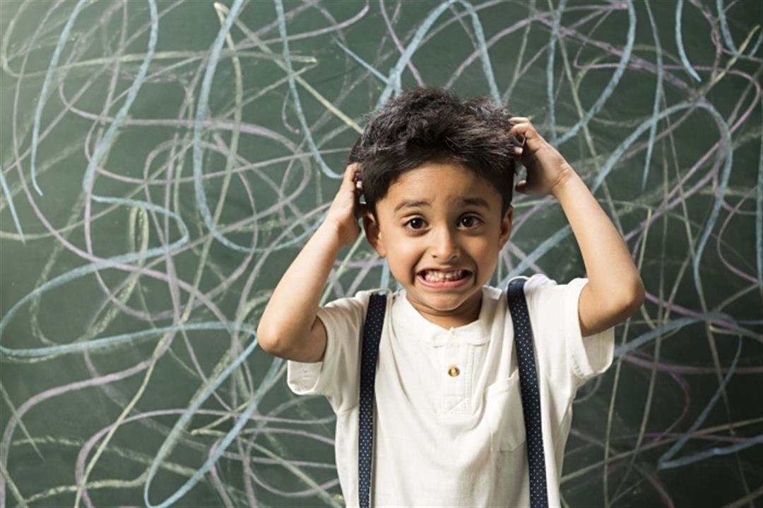 Child holding their hair in front of a chalkboard